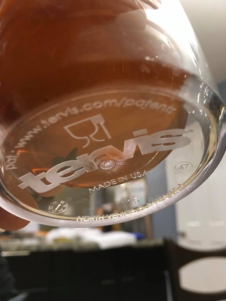 Close-up through the bottom of a clear Tervis cup showing a small clay figure inside the iced tea.