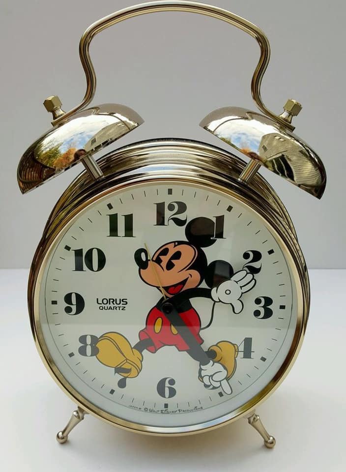 Vintage Mickey Mouse twin-bell alarm clock with a white face and gold-colored case.