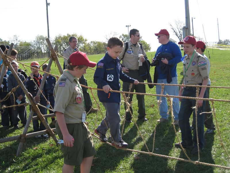 Scouts working together on an outdoor rope obstacle.