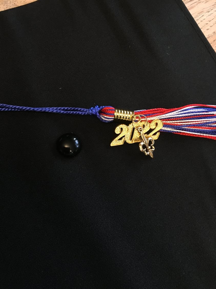 A 2022 graduation charm and cords displayed on dark fabric.