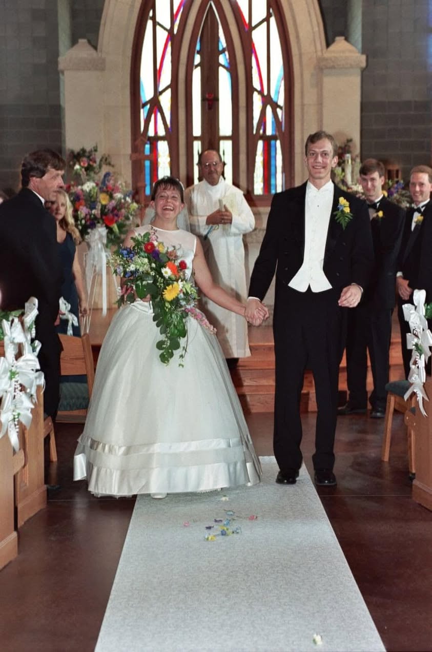 Bride and groom walking down a church aisle together after their wedding ceremony.