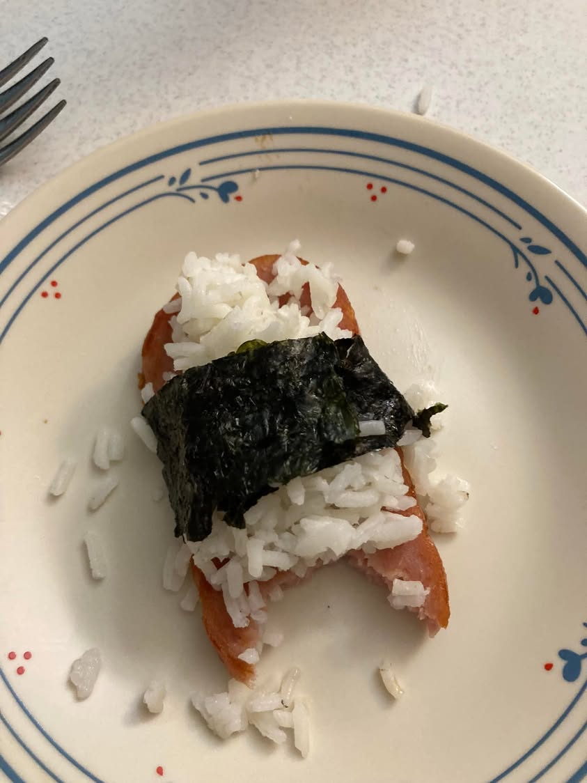 Homemade faux sushi made with rice, seaweed, and sliced Spam on a plate.