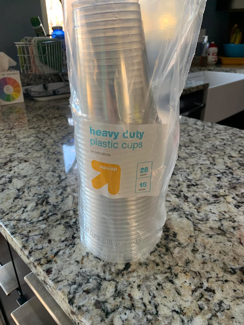 A package of clear heavy-duty plastic cups standing on a kitchen counter.
