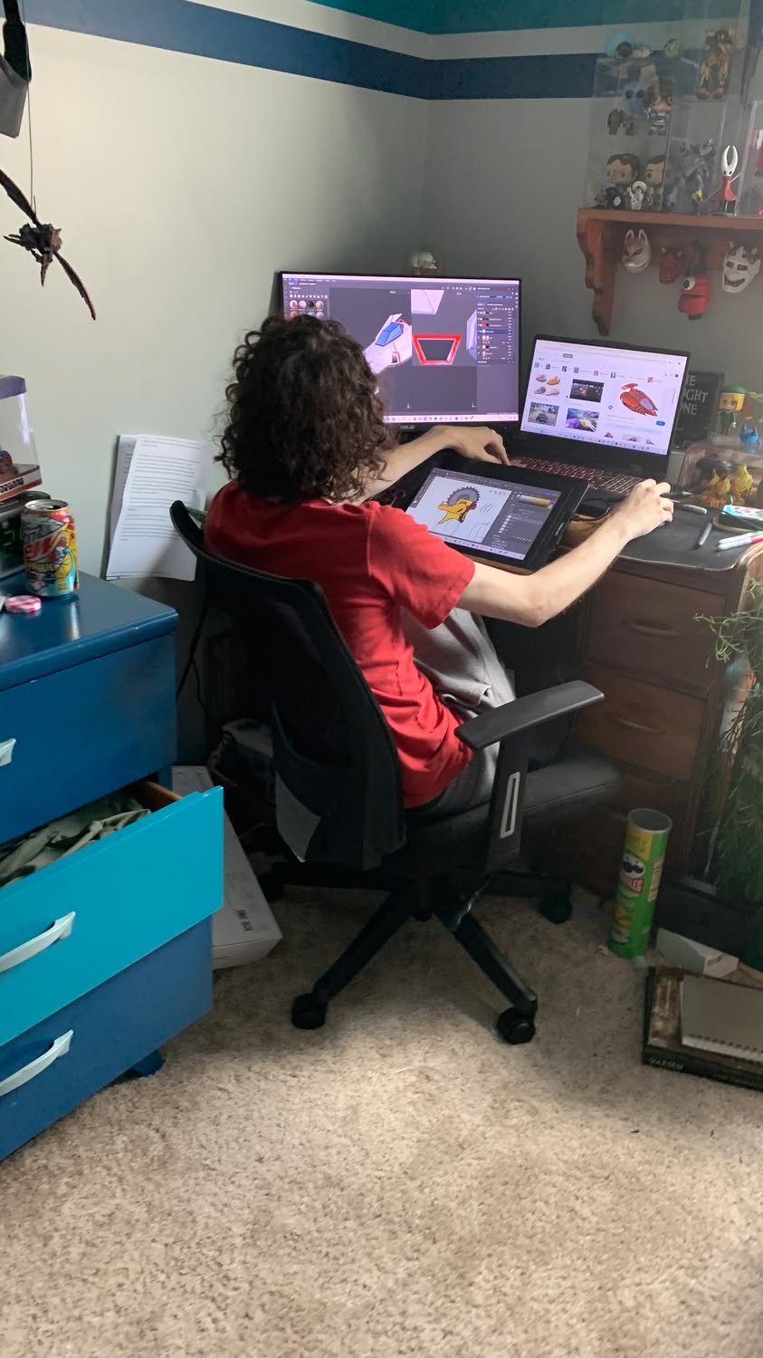 Young man seated at a computer workstation working on a digital 3D model.
