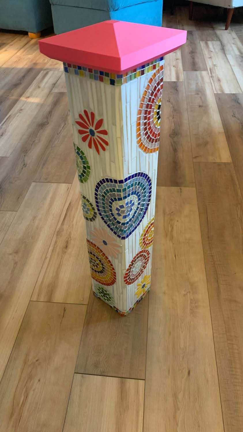 Decorative mosaic-covered column with a bright pink custom cap on top.