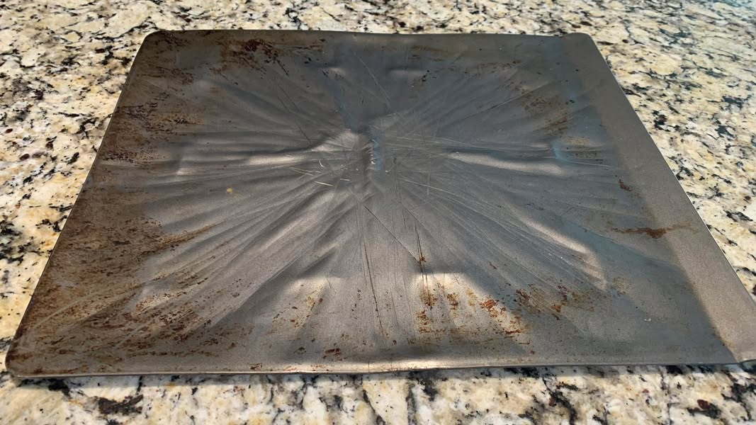 A well-used metal cookie sheet that has traveled through years of cooking and college life.